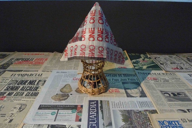 "One + One Hundred", 2017-2018. Video installation. 4'25'' HD video with audio, 50 covers and back covers of newspapers dated from 1953, hat made of newsprint, rubber stamp and wicker hatbox.