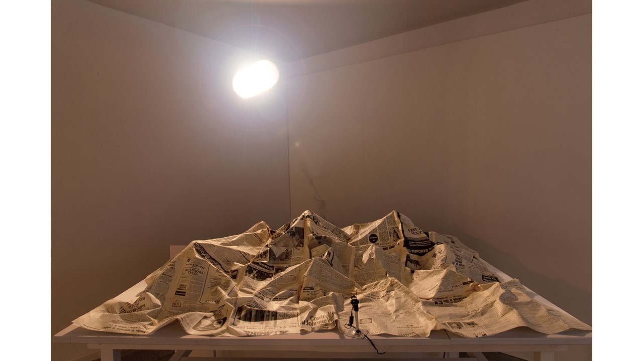 "Landscape (November 20, 1975)", 1999 Installation. Newspaper, table, lamp and motor, camera and projection.